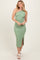 woman wearing a green and white striped sleeveless midi dress with a side slit and smiling at the camera