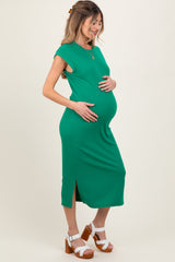 woman wearing a green ribbed maternity dress with side slits and holding her baby bump
