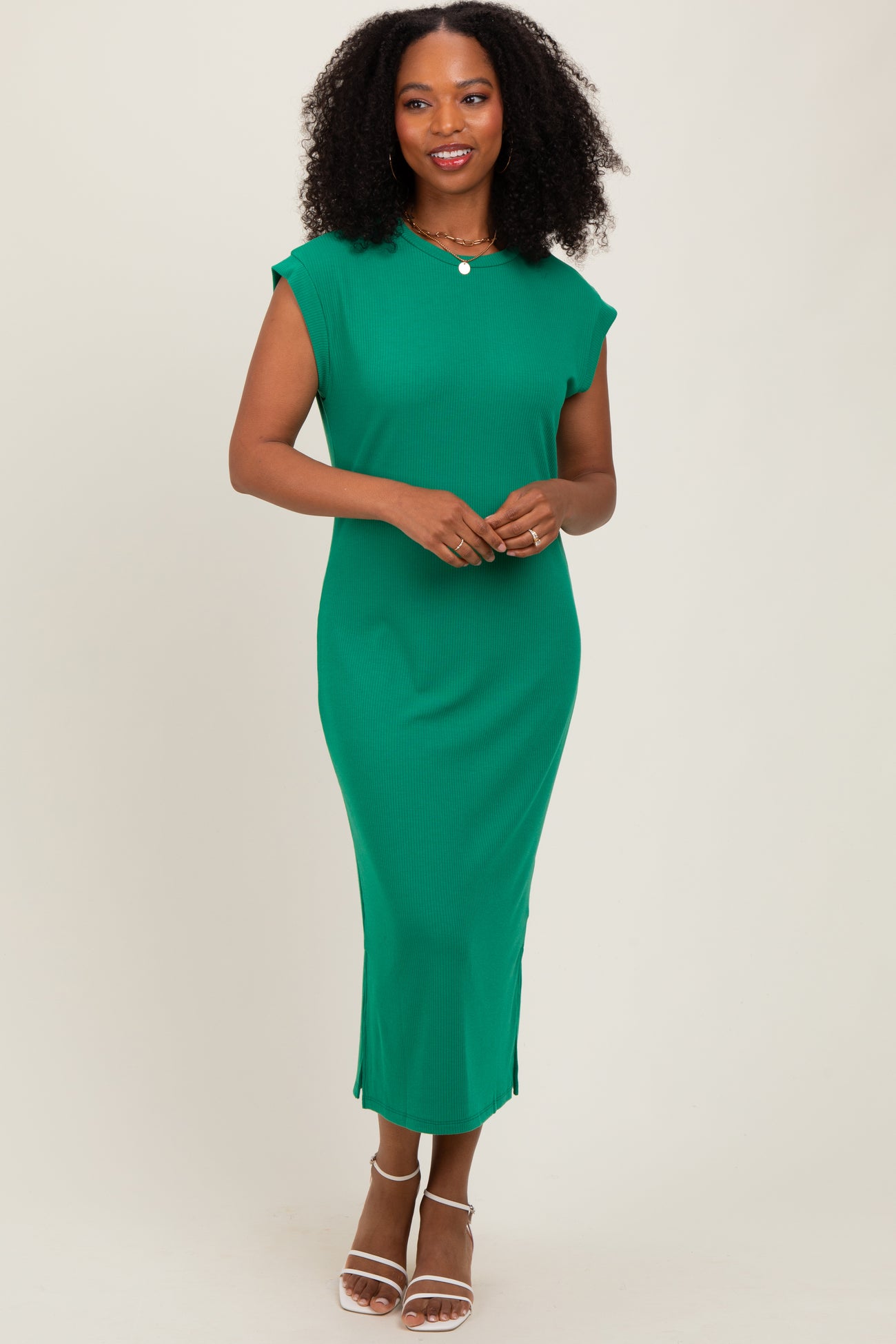 woman wearing a green ribbed midi dress with cap sleeves and side slits, standing and smiling