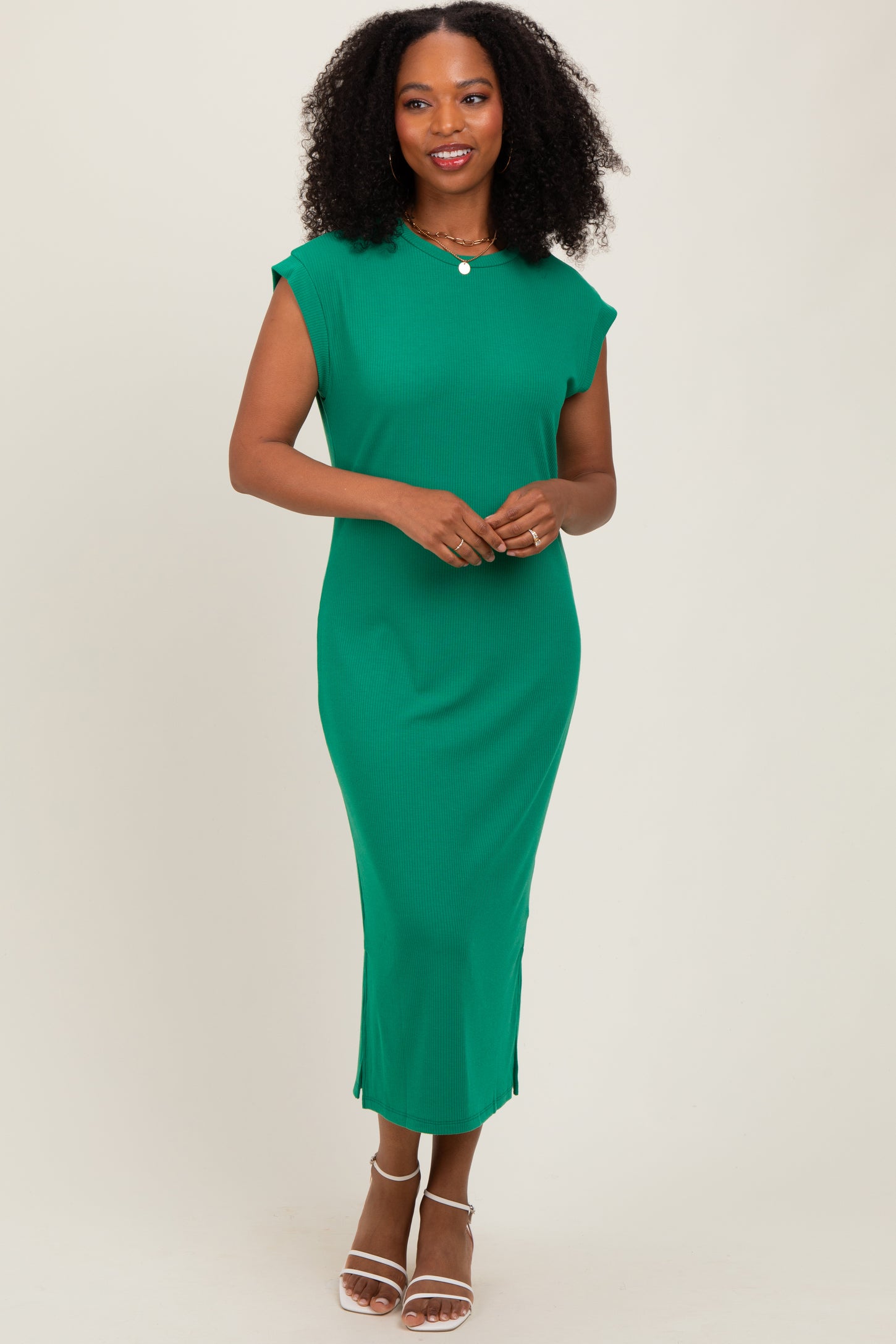 woman wearing a green ribbed midi dress with cap sleeves and side slits, standing and smiling