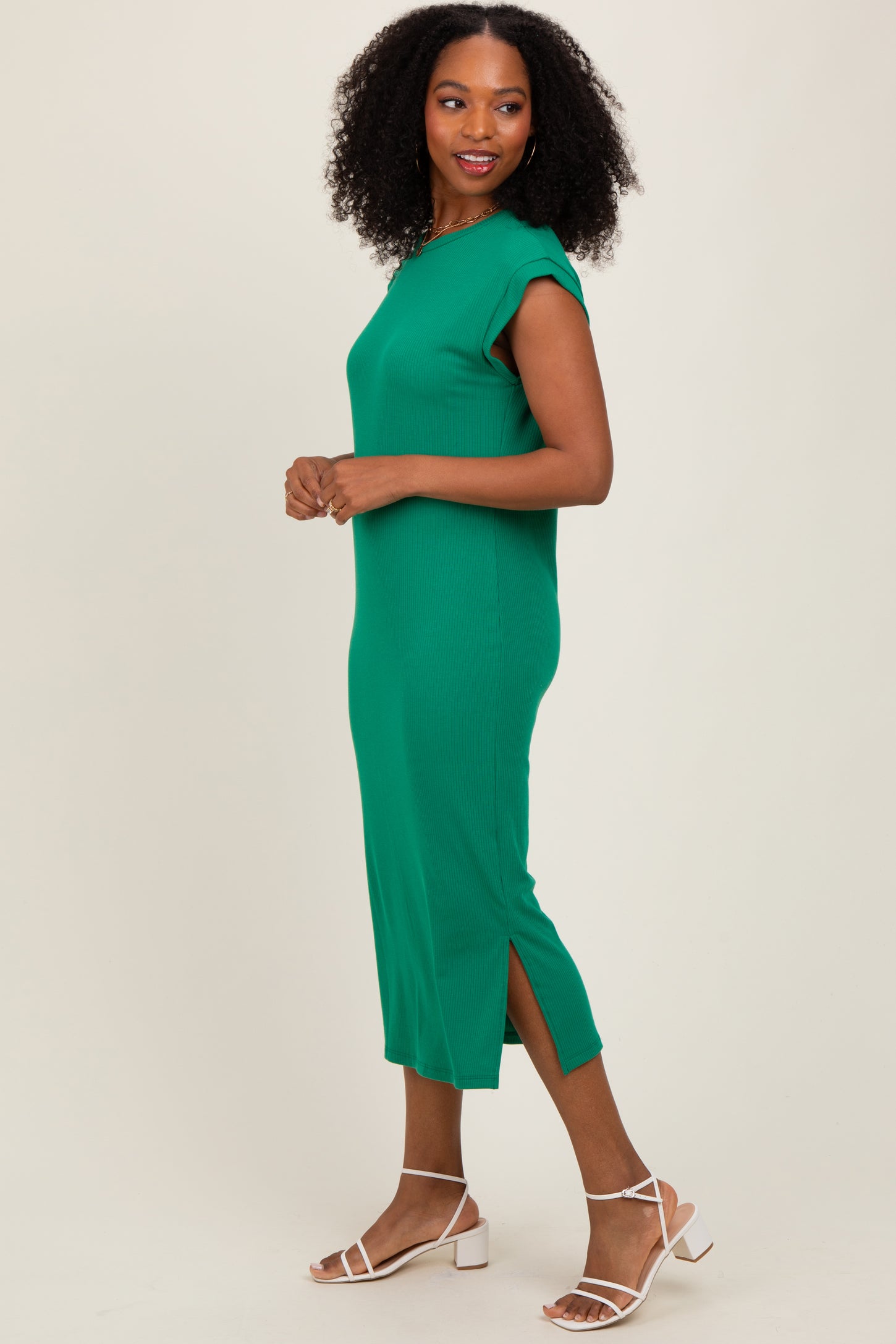 woman wearing a green midi dress with cap sleeves and side slits, standing in profile