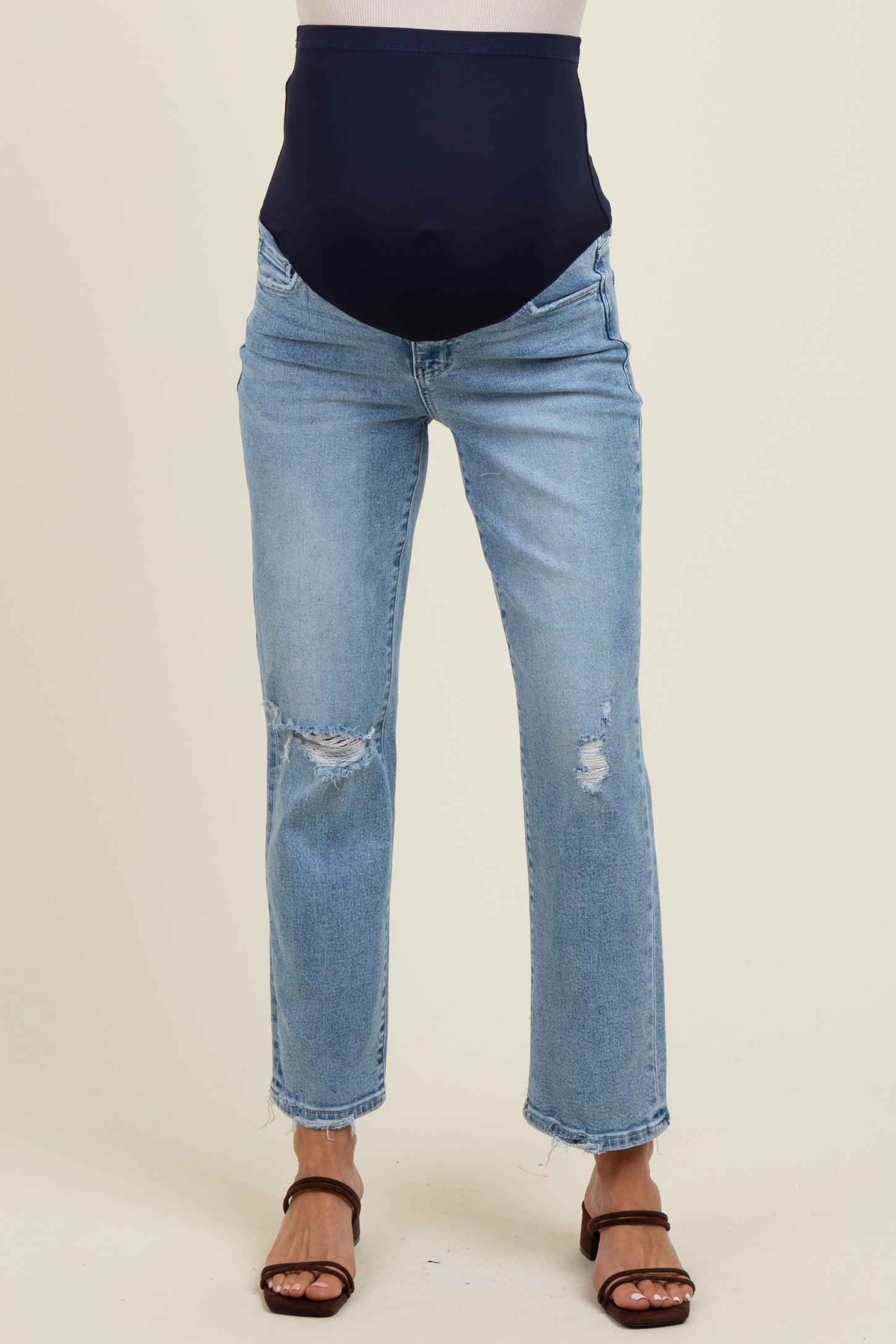 woman wearing light blue maternity jeans with a navy blue over-the-bump panel and distressed details