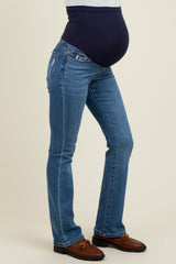 woman wearing dark blue maternity jeans with a supportive belly band and a slight flare at the bottom, showing a baby bump