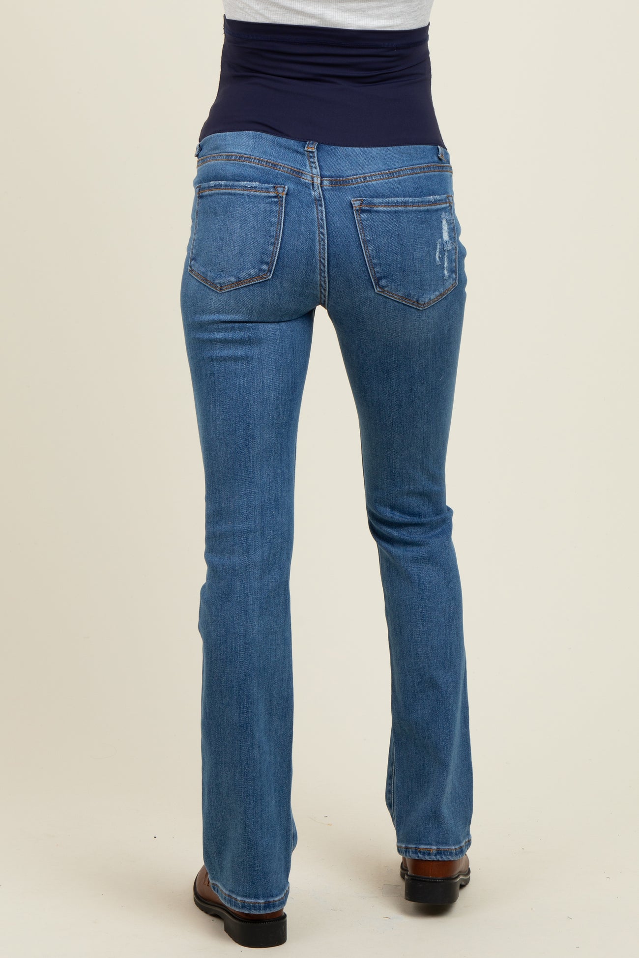 woman wearing a pair of blue maternity jeans with a supportive belly panel, showing the back view
