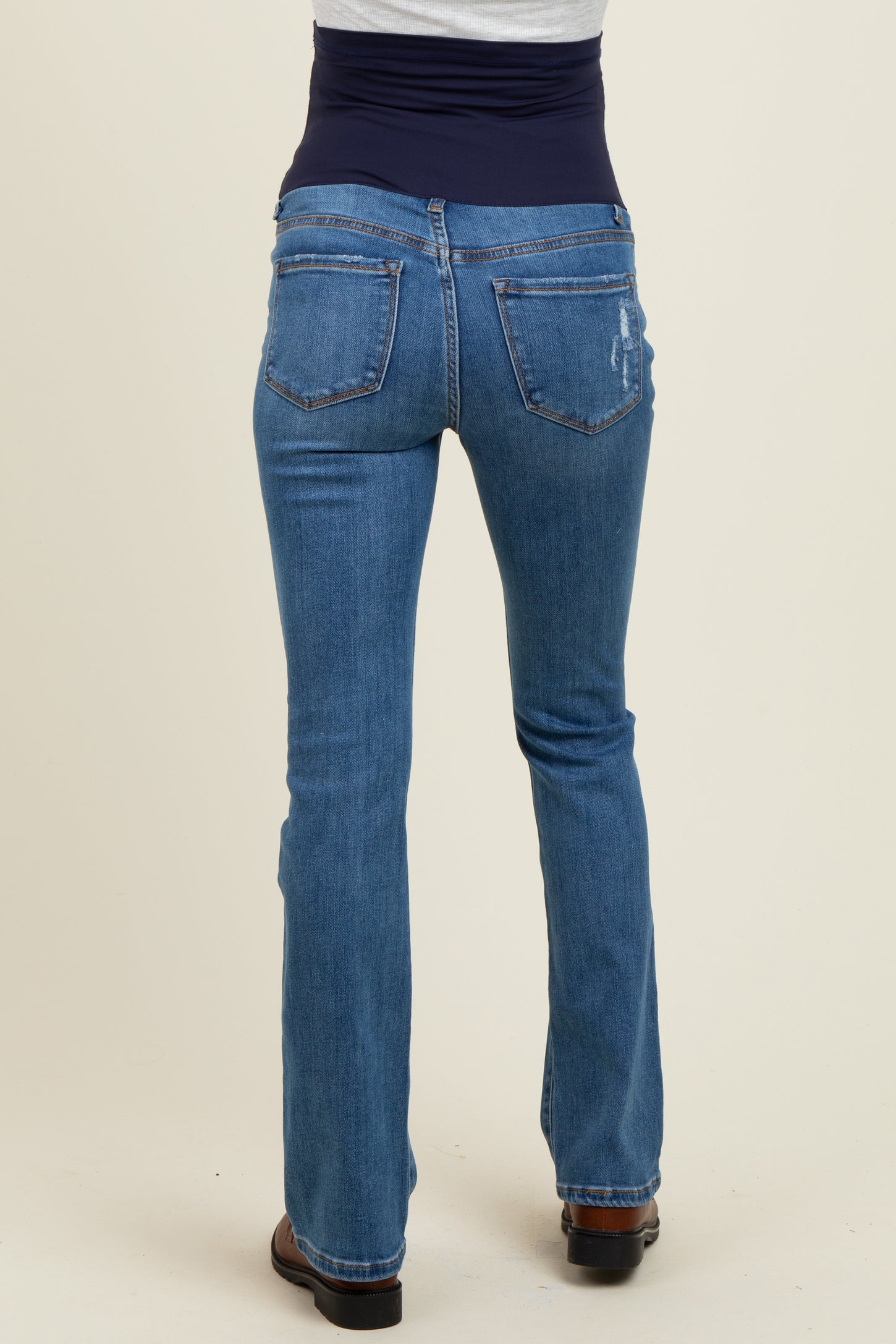 woman wearing a pair of blue maternity jeans with a supportive belly panel, showing the back view