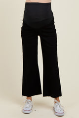 woman wearing black maternity wide-leg pants with a high waistband and frayed hem, showing a baby bump
