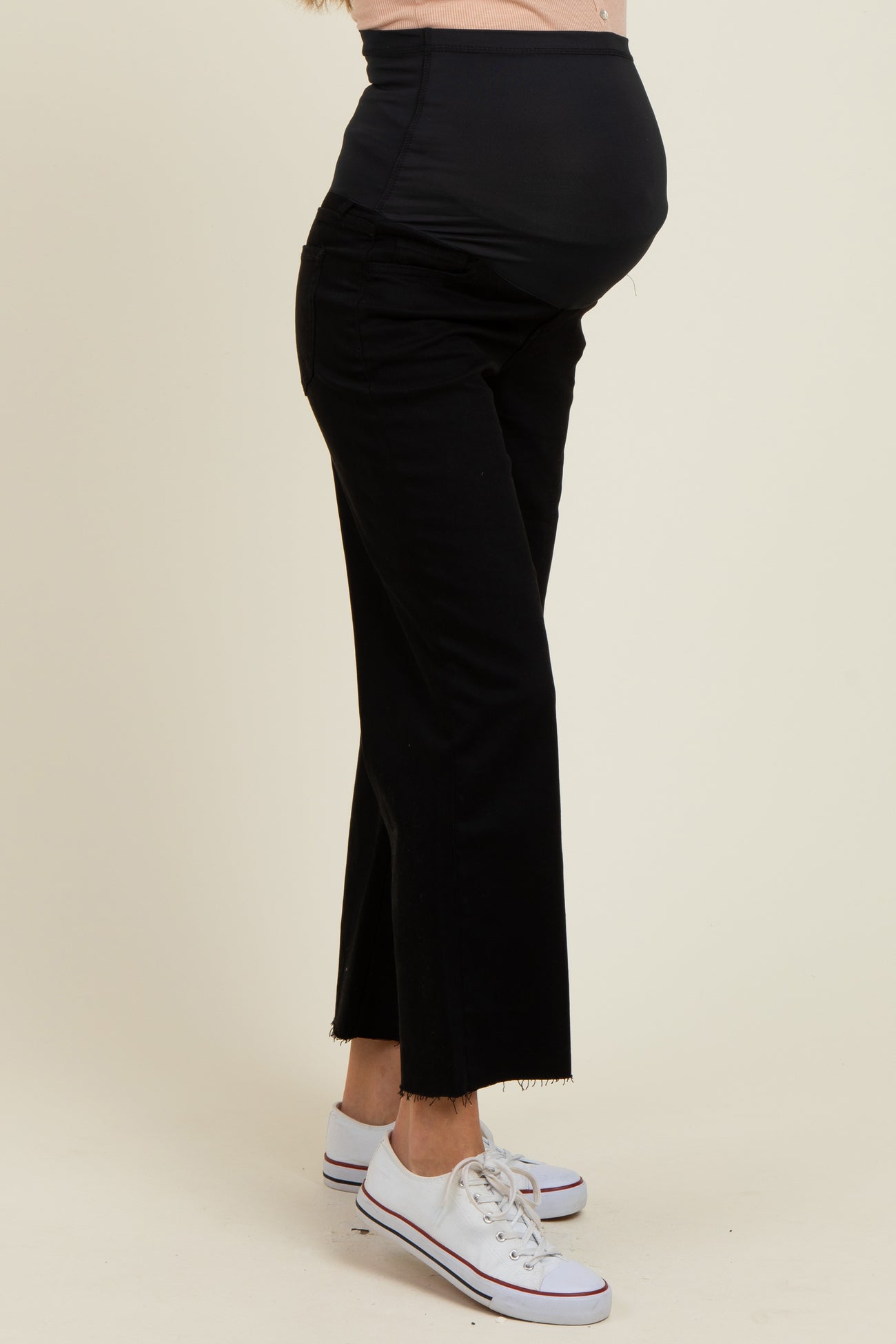 woman wearing black maternity jeans with a fitted belly panel and frayed hem, showcasing her baby bump