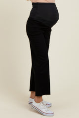 woman wearing black maternity jeans with a fitted belly panel and frayed hem, showcasing her baby bump