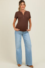 woman wearing a brown maternity henley top and light blue flared jeans, showing her baby bump