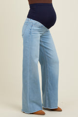 woman wearing light blue maternity jeans with a high waist and flared legs, showcasing a visible baby bump
