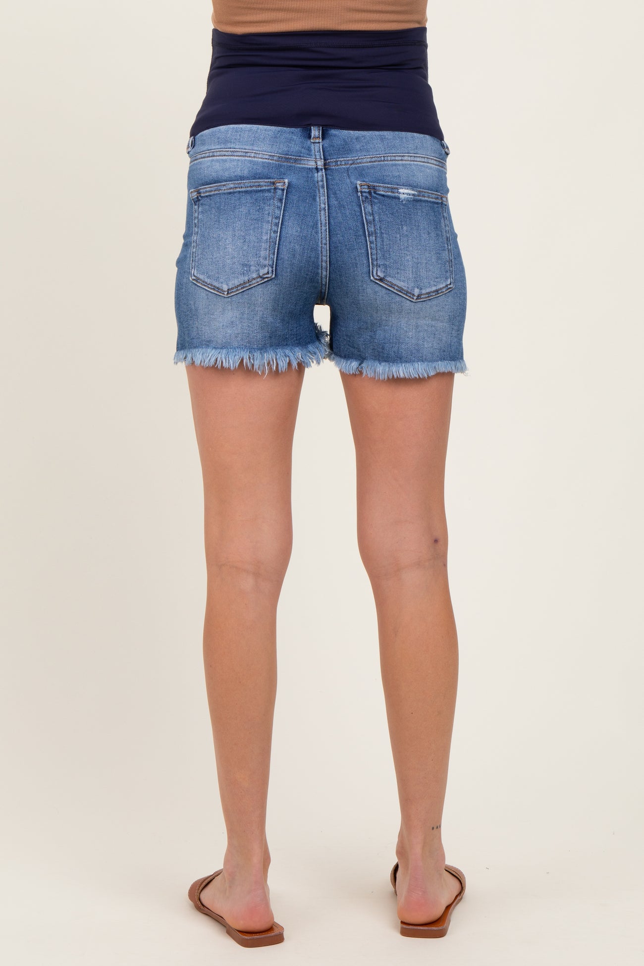 woman wearing a pair of blue maternity denim shorts with frayed hem, showing off her baby bump from behind