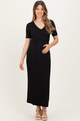 woman wearing a black short sleeve maternity dress with a v-neck and tie detail, holding her baby bump