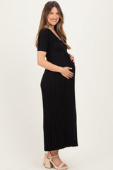woman wearing a black ribbed maternity maxi dress and holding her baby bump