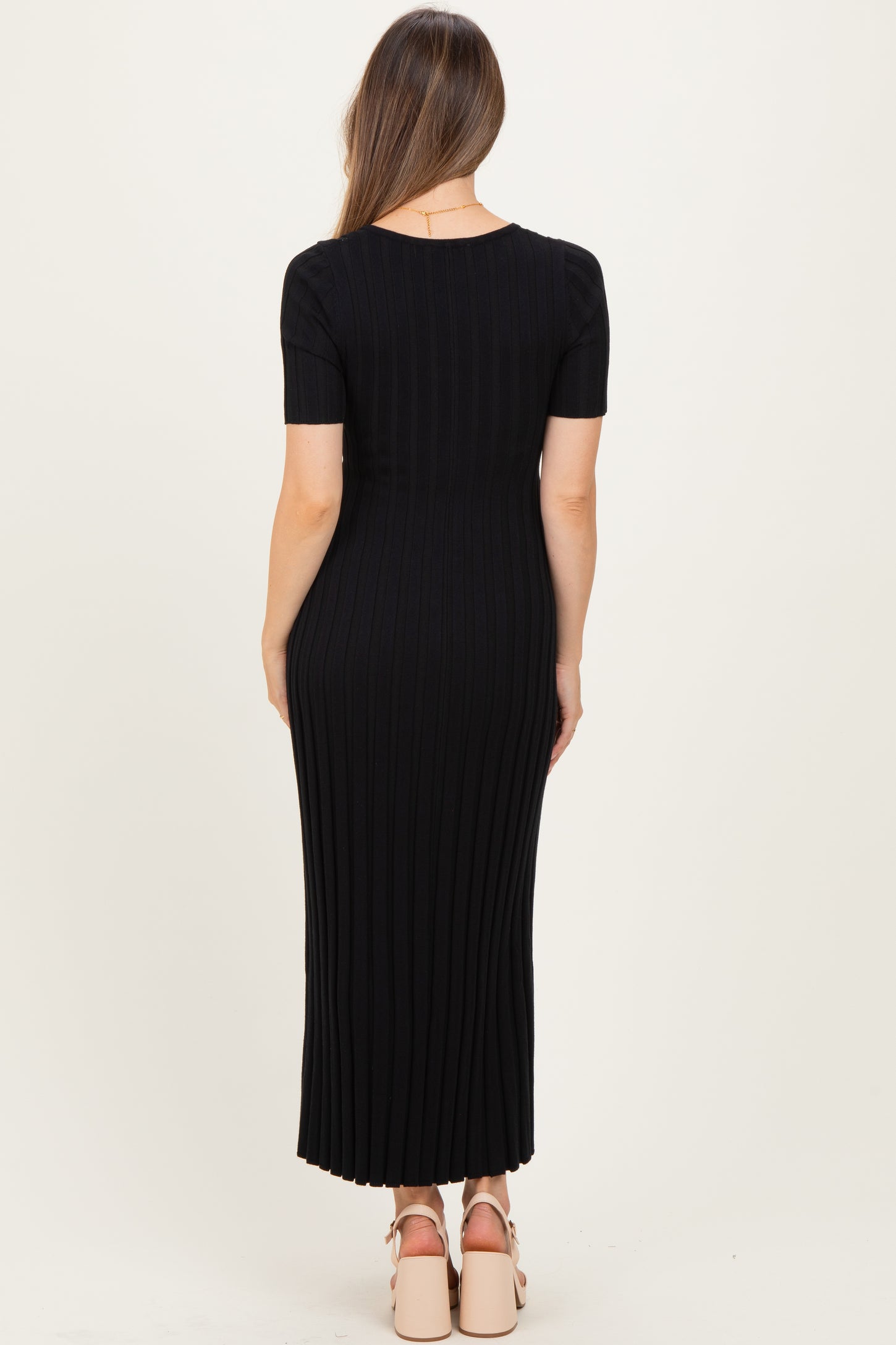 woman wearing a black ribbed maternity maxi dress with short sleeves, showing a fitted silhouette from the back