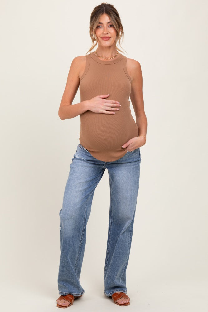 woman wearing a tan ribbed maternity tank top and blue flared jeans, holding her baby bump
