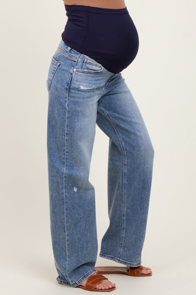 woman wearing light blue distressed maternity jeans with a black belly band and showing her baby bump