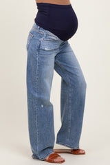 woman wearing light blue distressed maternity jeans with a black belly band and showing her baby bump