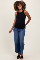 woman wearing a black maternity tank top and blue wide-leg jeans with a visible baby bump