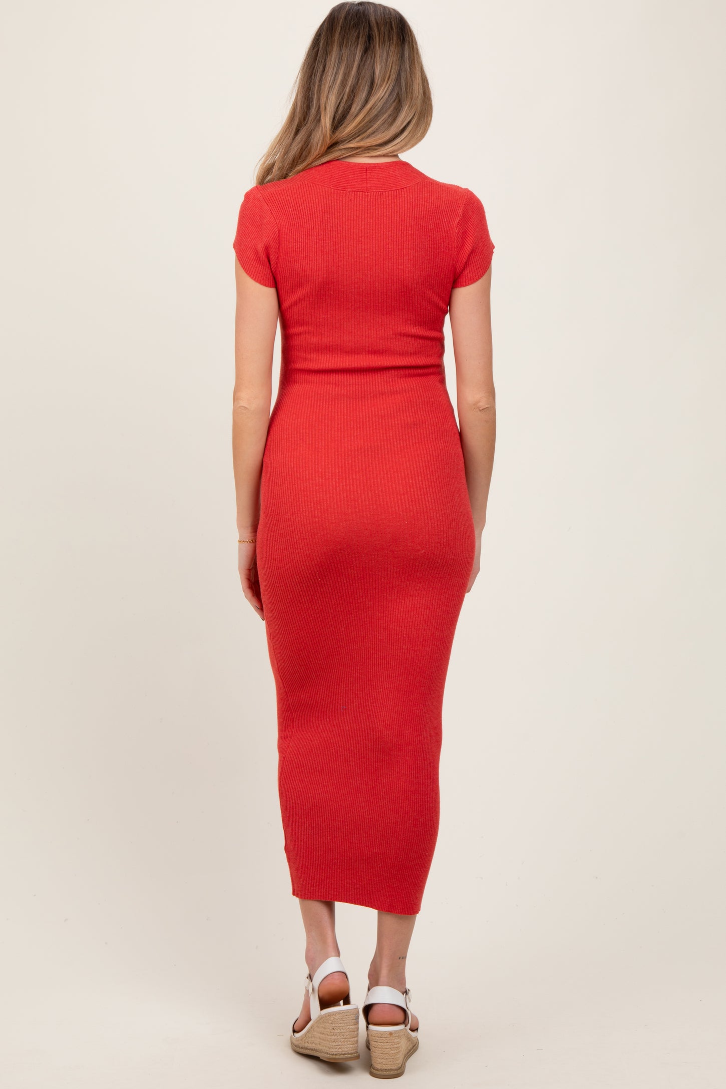 woman wearing a red ribbed maternity dress with short sleeves and a fitted silhouette, viewed from the back