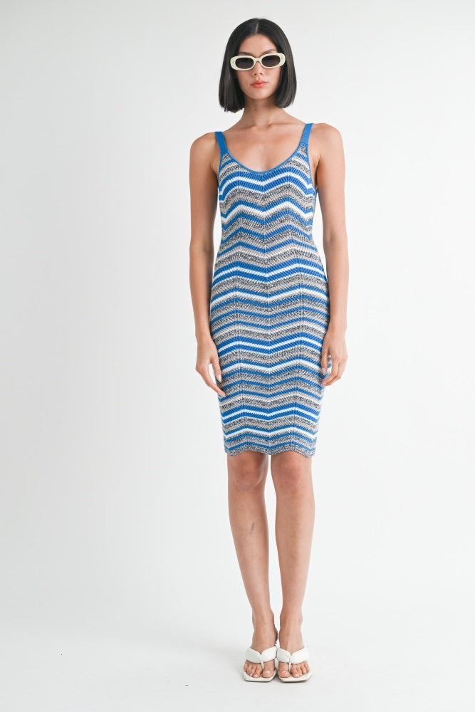 woman wearing a fitted blue and white zigzag patterned knit dress and oversized sunglasses