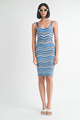 woman wearing a fitted blue and white zigzag patterned knit dress and oversized sunglasses
