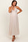 woman wearing a light beige maternity maxi dress with a halter neck and a fitted bodice, showing her baby bump