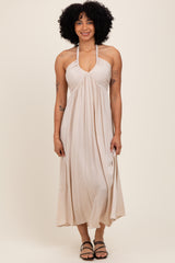 woman wearing a beige halter neck maxi dress with gathered detailing and slim straps