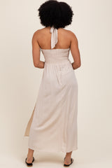 woman wearing a backless cream maxi dress with a smocked bodice and side slit