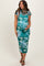 woman wearing a green floral print maternity dress and cradling her baby bump