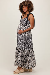 woman wearing a black and white patterned maternity maxi dress with tie straps and a visible baby bump