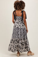 woman wearing a black and white patterned maternity maxi dress with tie straps and a tiered hemline