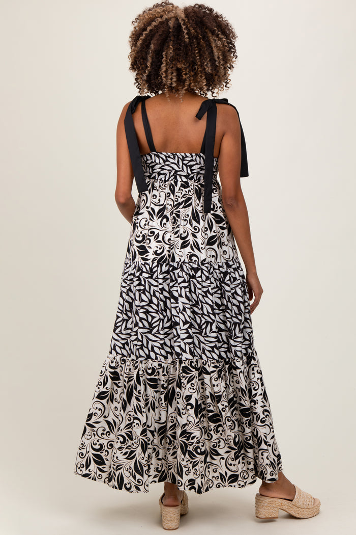 woman wearing a black and white patterned maternity maxi dress with tie straps and a tiered hemline
