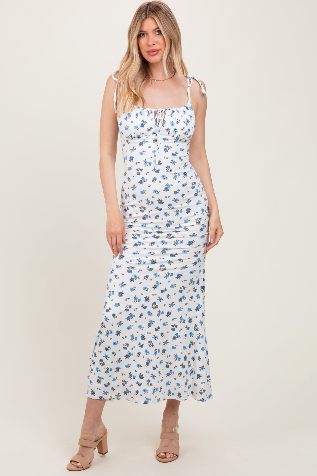 woman wearing a white floral maxi dress with tie straps and ruching details