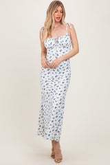 woman wearing a white floral maxi dress with ties at the shoulders and a fitted silhouette