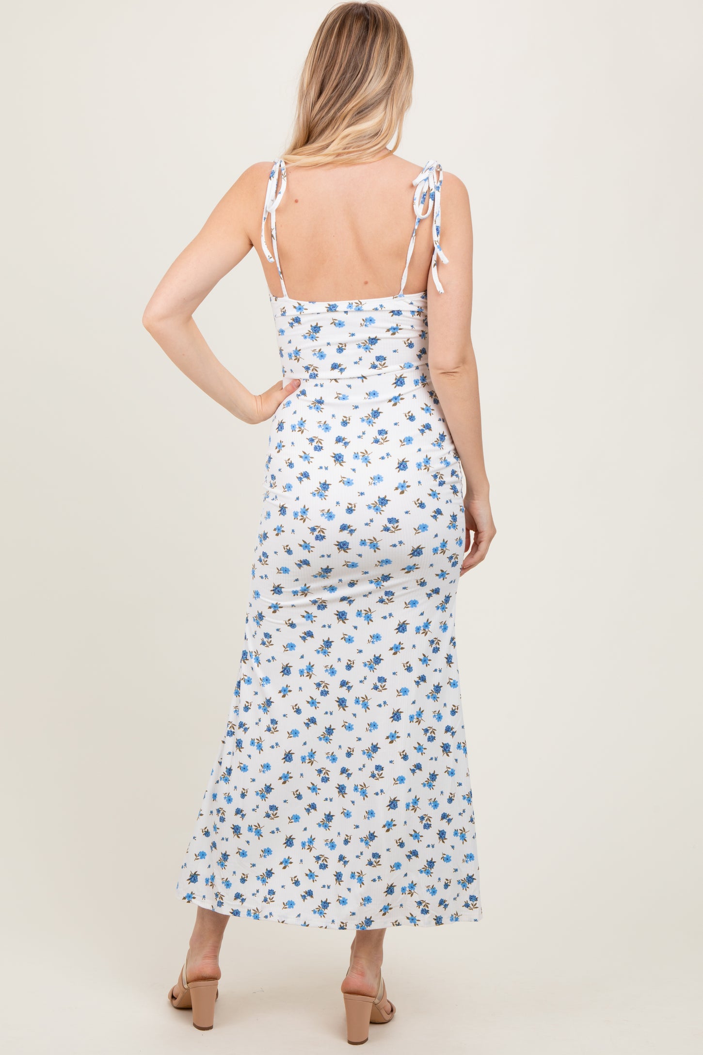 woman wearing a white floral maxi dress with adjustable tie straps and a fitted bodice, shown from the back