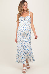 woman wearing a white floral maternity dress with adjustable straps and a fitted silhouette, showing her baby bump