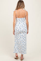 woman wearing a white floral maternity maxi dress with tie straps and a fitted bodice, showing a baby bump