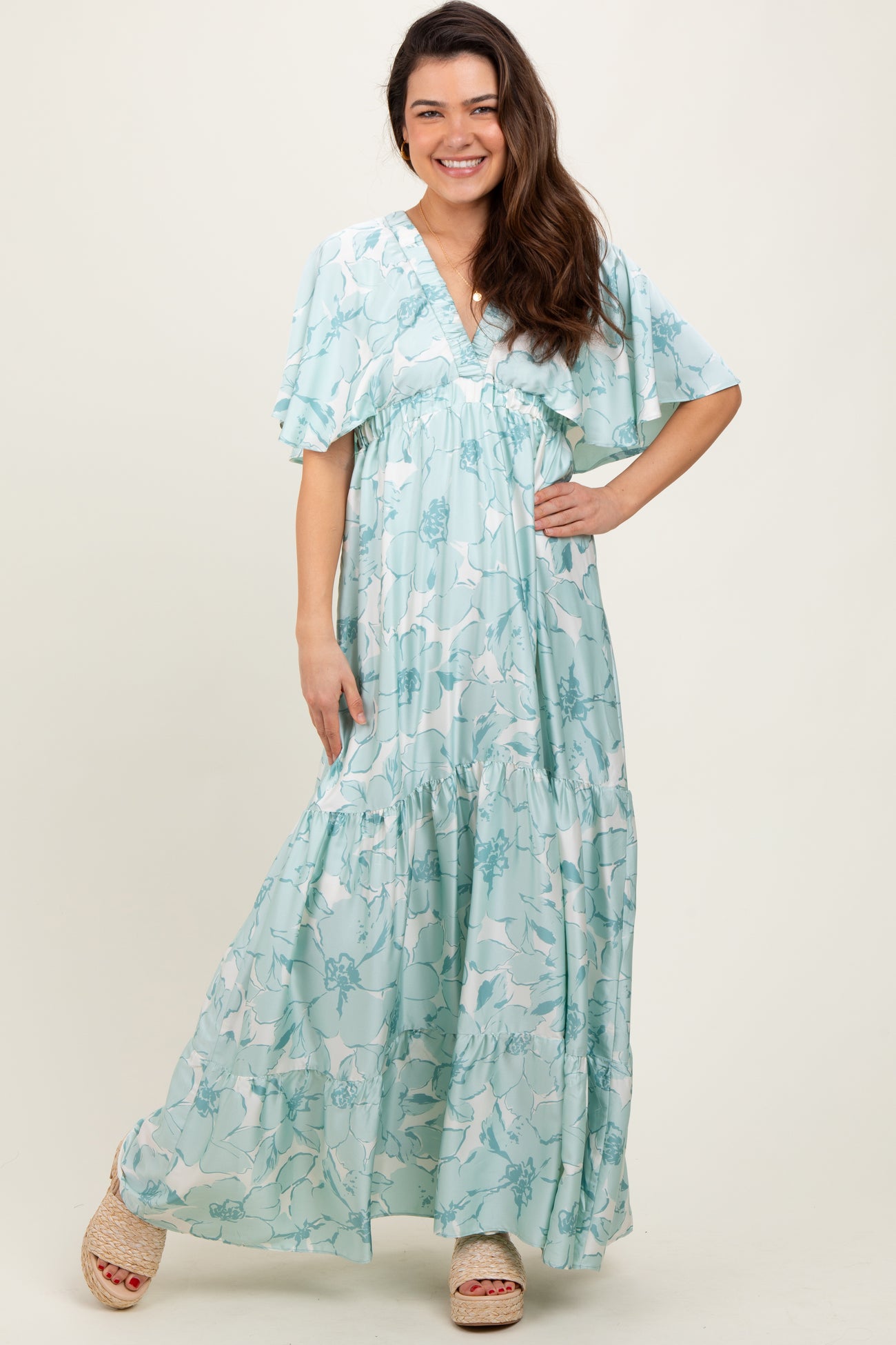 woman wearing a light blue floral maxi dress with flutter sleeves and a tiered skirt