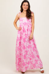 woman wearing a pink floral maxi dress with adjustable straps and a fitted bodice