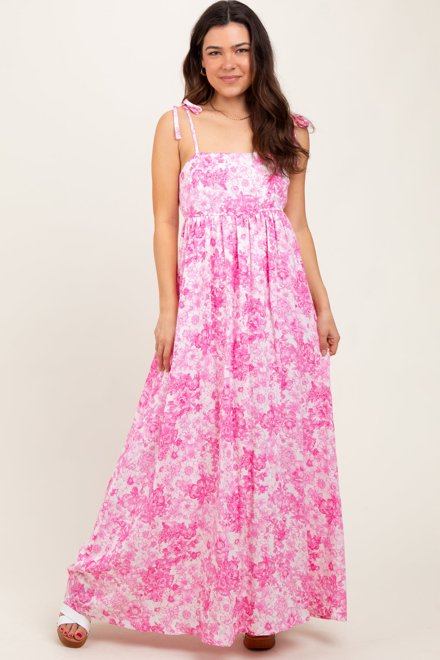 woman wearing a pink floral maxi dress with spaghetti straps and a flowy skirt