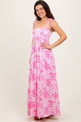 woman wearing a pink floral maxi dress with tie shoulder straps and a flowy silhouette