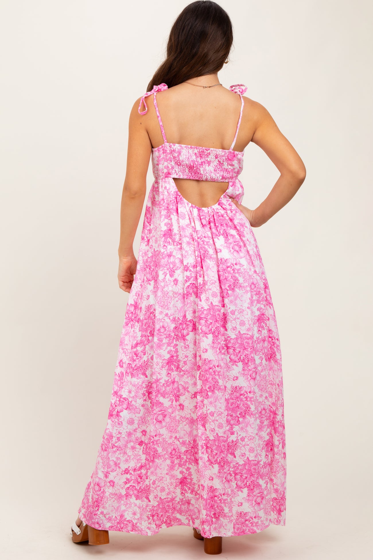 woman wearing a pink floral maxi dress with a scoop back and adjustable tie straps