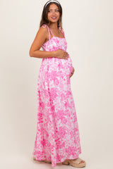 woman wearing a pink floral maxi maternity dress and holding her baby bump