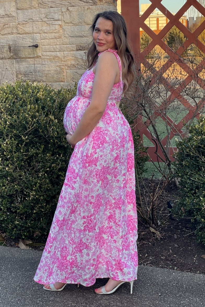 woman wearing a pink floral maternity maxi dress and showing her baby bump