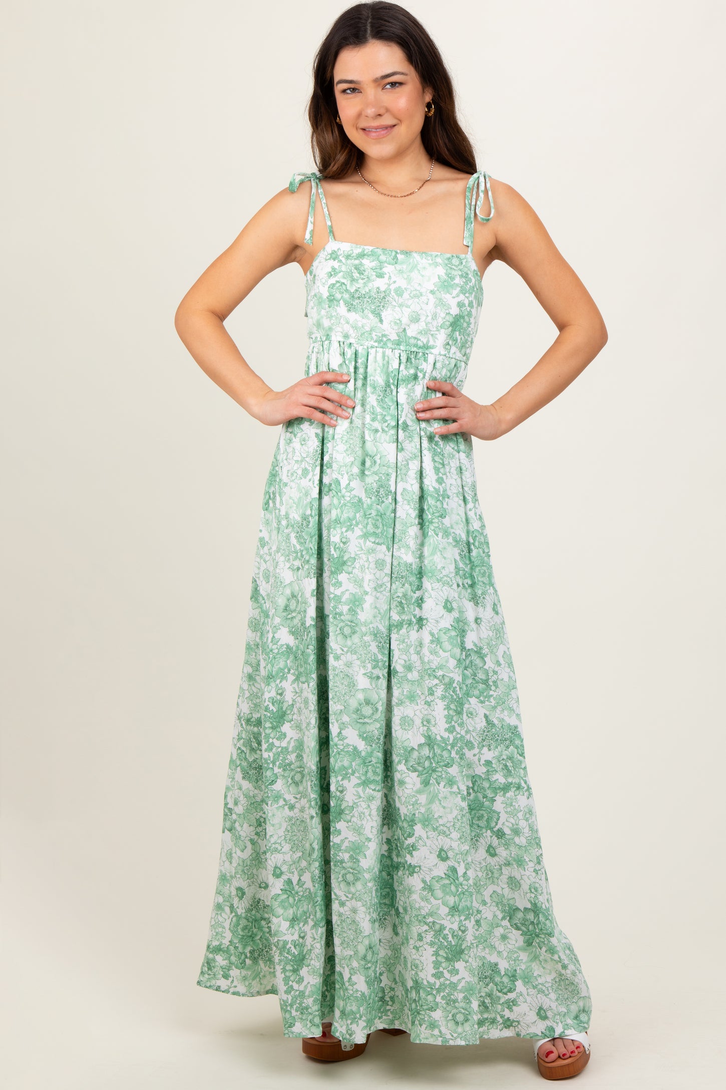 woman wearing a green floral maxi dress with tie straps and a flowy silhouette