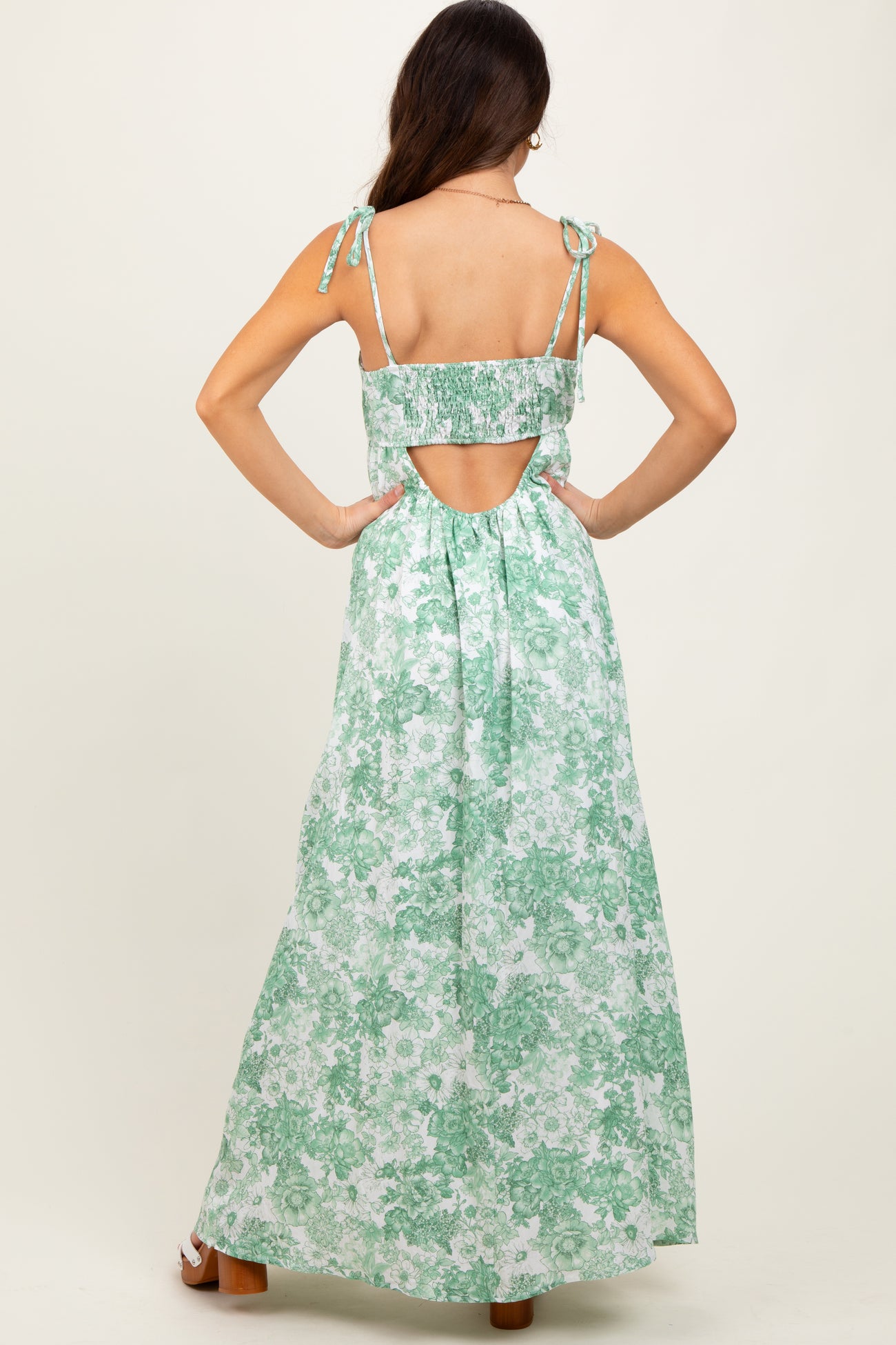 woman wearing a green floral maxi dress with adjustable tie straps and an open back detail