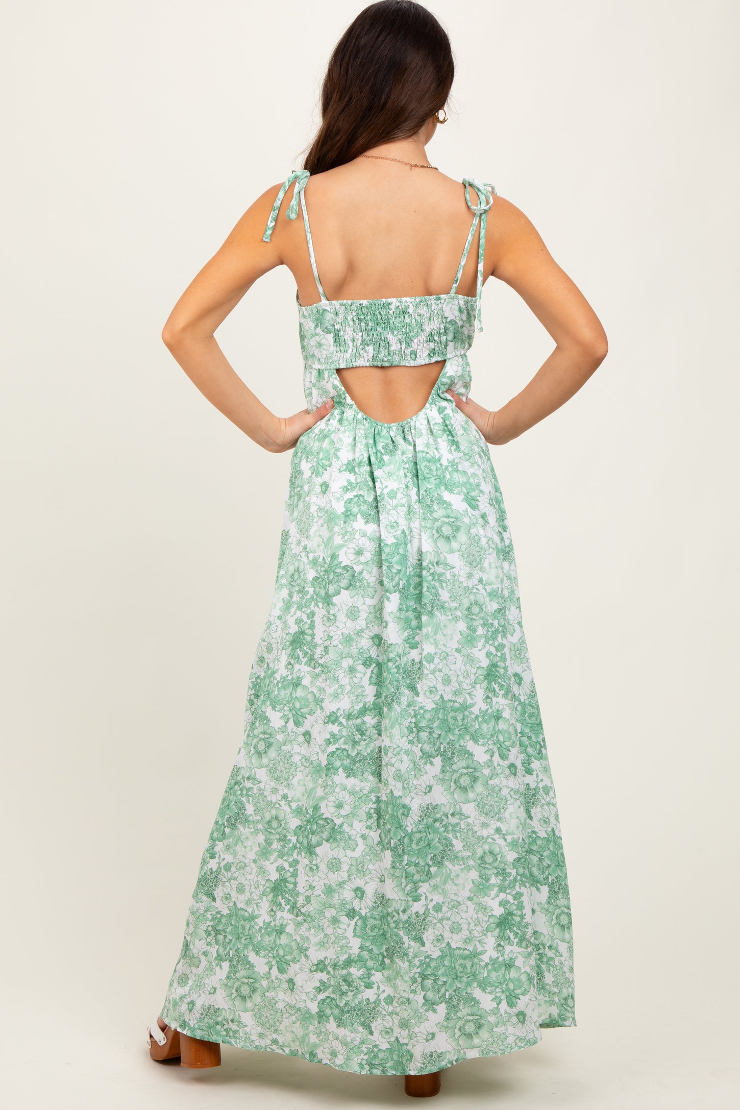 woman wearing a green floral maxi dress with adjustable tie straps and an open back detail
