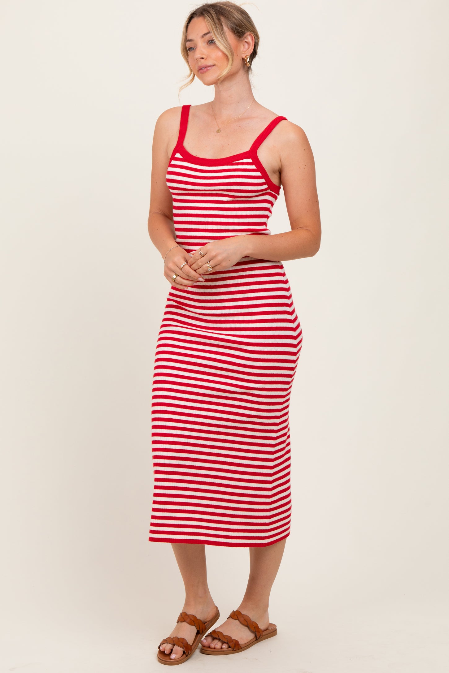 woman wearing a red and white striped sleeveless midi dress with a fitted silhouette and a scoop neckline