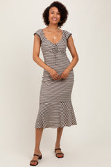 woman wearing a black and white striped midi dress with a scoop neckline and cap sleeves, styled casually with sandals