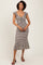 woman wearing a black and white striped midi dress with a scoop neckline and cap sleeves, styled casually with sandals